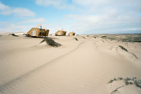 Wrakvormige houten lodge van Shipwreck Lodge tussen duinen en oceaan – Christoffel Travel